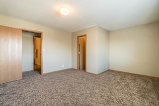 A room with carpeted floor and two doors.