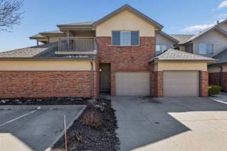 Exterior view of brick townhome with attached garages and upper balcony.