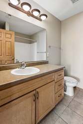 Bathroom with wood vanity, laminate countertop, toilet, and tub-shower.