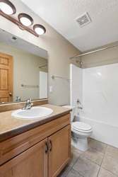 Bathroom with wood vanity, laminate countertop, and tub-shower.