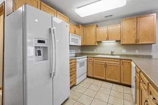 Updated kitchen with wood cabinetry, laminate counters, and overhead lighting.