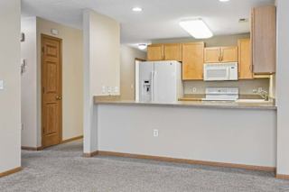 Kitchen featuring a wide peninsula counter, white refrigerator, and open layout.