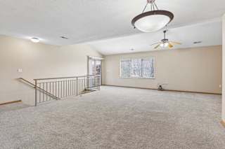 Spacious upstairs loft with carpeted floors and stairway railing.