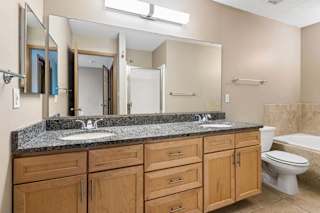 Bathroom with double vanity, granite countertop, large mirror, and tub-shower.