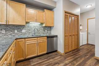 Kitchen area with granite counters, tile backsplash, and adjacent laundry closet.