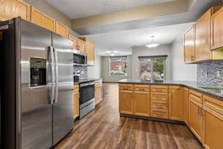 Modern open-concept kitchen with island, stainless steel range, and wood-style floors.