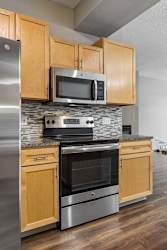Modern kitchen featuring stainless steel oven, microwave, and wood cabinets.