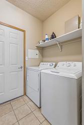 partment laundry room with full-size washer and dryer, shelving, and additional storage space.