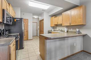 Open apartment kitchen featuring light wood cabinetry, breakfast bar, tile flooring, and ample prep space.