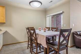 Dining area in an apartment home with table seating, neutral walls, and sliding glass door access nearby.