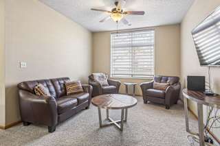 Spacious apartment living room with plush carpet, large window, fireplace, and open sightlines to the dining area.