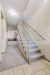 Apartment entry hallway with carpeted staircase, neutral finishes, and open layout leading to the main living area.