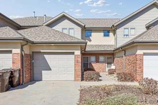 Townhome-style apartment exterior with attached garage, brick accents, and private driveway.