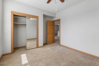 Bedroom interior highlighting a mirrored sliding-door closet with built-in shelf and hanging rod, plus warm wood trim.