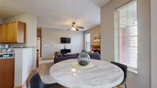 an open living room and dining room with a marble table and a ceiling fan