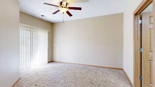 a bedroom with sliding doors to a balcony and a ceiling fan
