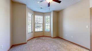 a bedroom with three windows and a ceiling fan