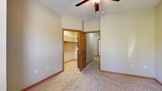 a bedroom with a ceiling fan and doors to the walk-in closet and hallway