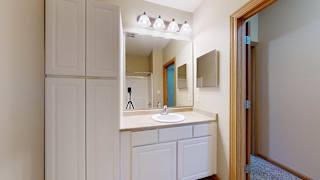a bathroom with a vanity sink, a mirror, overhead lighting, and white storage cabinets