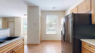 a kitchen with a black refrigerator, a swan stone sink, and a window
