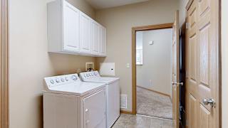 a laundry room with a washer and dryer and a door to the hallway