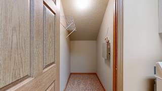 a storage closet next to the laundry room with a built-in wire shelf