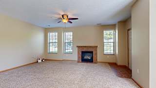 a living room with a ceiling fan, a brick/tile fireplace, three tall windows, and a tiled entryway.