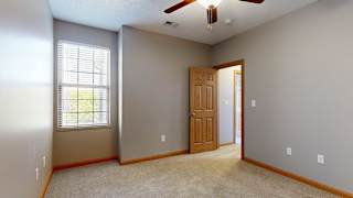 a bedroom with a tall window and a ceiling fan