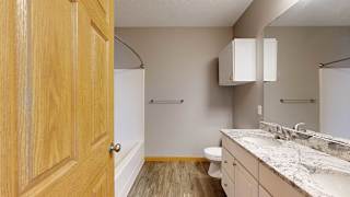 a bathroom with tub and shower, a toilet, and double sink with granite countertops and a mirror