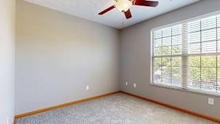 a bedroom with a large window and a ceiling fan