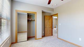 a bedroom with a closet, large window, and ceiling fan