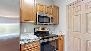 a kitchen with a stove and microwave and wooden cabinets and a granite countertop