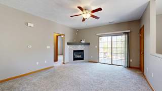 a living room with a fireplace, sliding glass doors to a balcony, and a ceiling fan