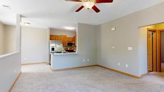 a living room with a ceiling fan adjacent to a galley kitchen