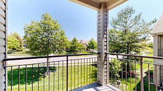 a balcony with a view of a grassy area below and trees
