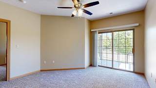 a bedroom with a ceiling fan and sliding glass door to a balcony