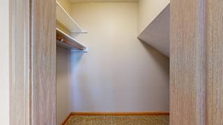 a walk-in closet with a built-in shelf and an angled alcove