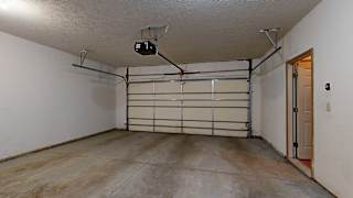 a 2-car garage with white walls and a door to the apartment