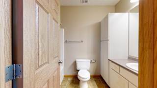 a bathroom with a toilet, a sink, and tall storage cabinets