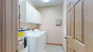 a laundry room with side-by-side washer and dryer and overhead storage