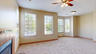 a living room with a ceiling fan, several windows, and a fireplace