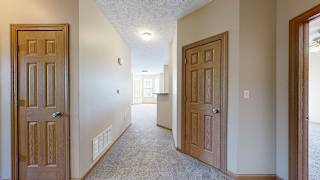 a hallway with doors to a mechanical closet, coat closet, and primary bedroom