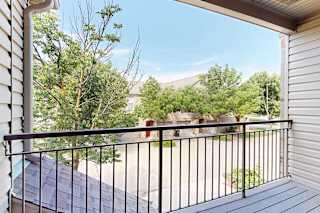 A balcony with a black railing overlooks nearby apartments at Stone Creek Villas.
