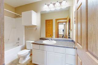 A bathroom with a white cabinets, a large mirror, and a tub shower.