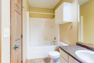 A bathroom with a vanity sink, an overhead storage cabinet, and a tub shower.