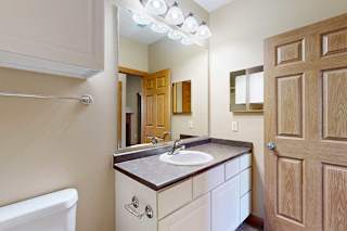 A bathroom with a sink, mirror, and overhead lighting..