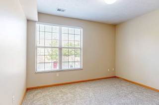 A carpeted bedroom with a large window and blinds.