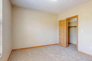 A carpeted bedroom with a large window, and a walk-in closet.