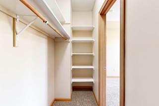 A walk-in closet with several built-in shelves and a long overhead shelf and hanging space.