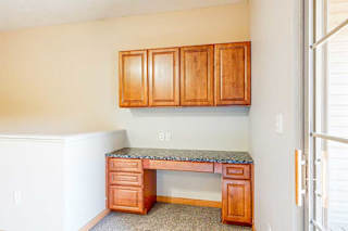 A built-in desk with wooden cabinets and a granite counter in the living room.